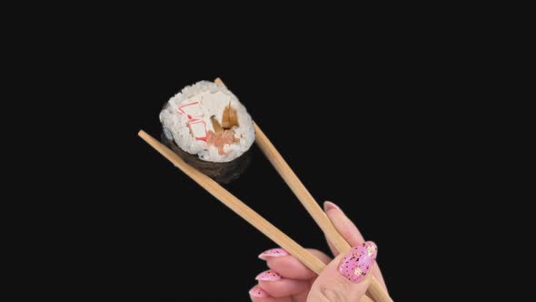 Female Hands Hold Japanese Chopsticks with Sushi Rolls on Transparent Background