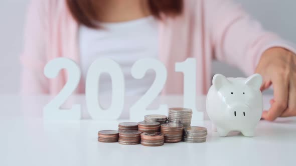 Stack of coins with young woman putting coin into the piggy bank