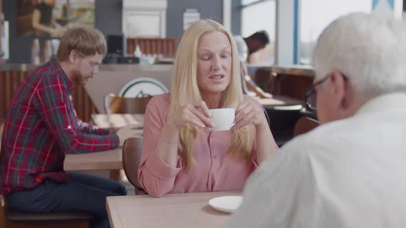 Senior Couple Drink Coffee and Talk in Restaurant