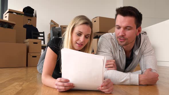 A Smiling Moving Couple Lies on the Floor of an Empty Apartment and Talks About a Bunch of Papers