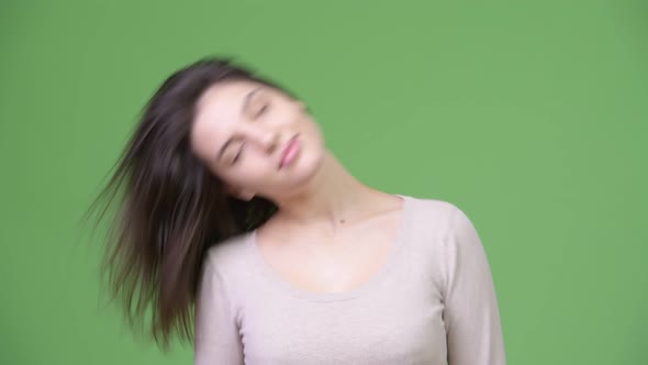 Young Beautiful Woman Flipping Hair Against Green Background