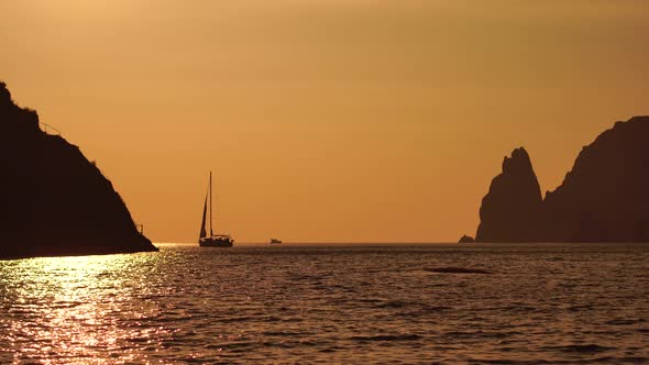 A Red Burning Sunset with the Silhouette of a Cliff Over the Sea