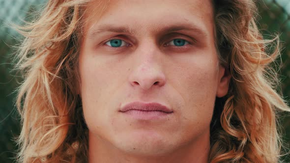 portrait of handsome blue-eyed guy with blond long curly hair