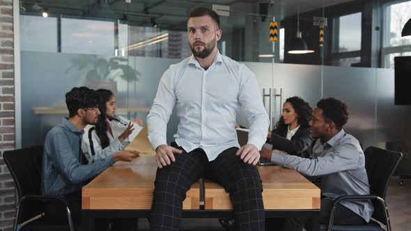 Chaotic Coworkers in Background Arguing Multiracial Colleagues in Boardroom Young Frustrated Man