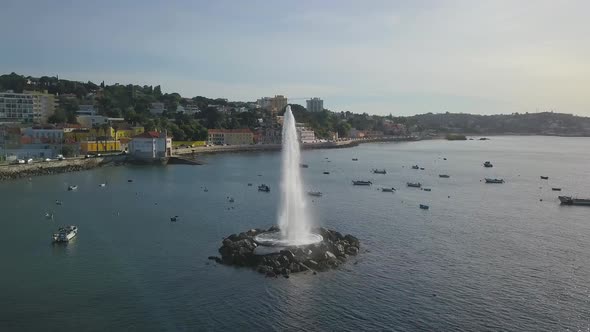 Aerial drone view around the ocean Fountain with Oeiras in background, in Paço de Arcos, sunny day,