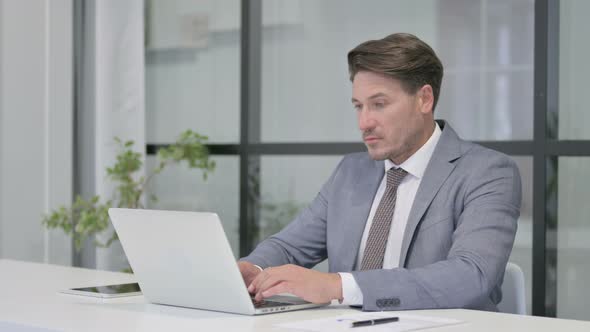 Middle Aged Man Working on Laptop in Office