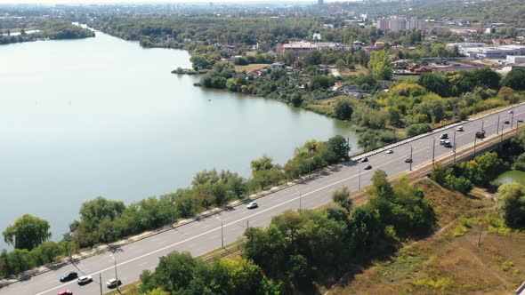 Aerial Shot of Road Traffic Passing on Bridge Over River Against a Background of Trees and Houses on