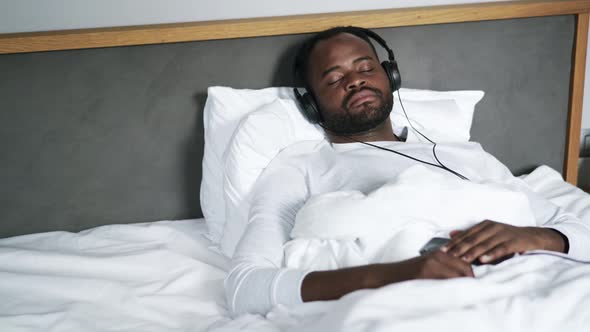 African man sleeping in headphones