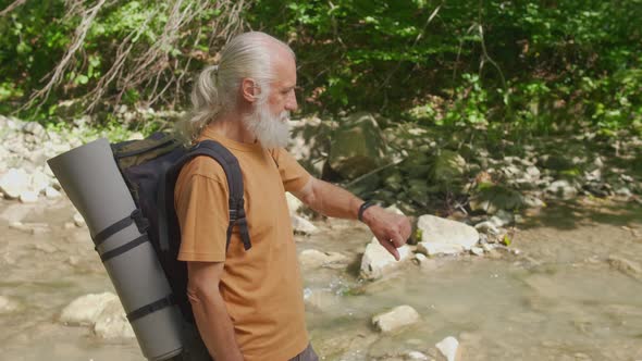 Old Man Uses Bracelet and Mobile Phone While Traveling in the Forest