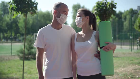 Positive Sportsman and Sportswoman in Covid-19 Face Masks Looking at Each Other and Talking