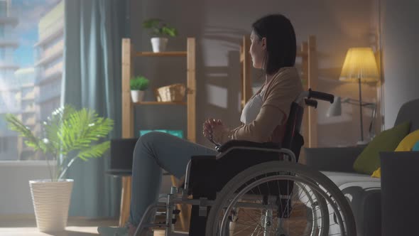 Portrait of a Lonely Disabled Woman in an Apartment on a Sunny Day Looking Out the Window