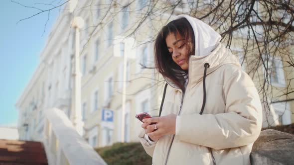 Attractive African American Teenage Girl Using Mobile Phone During Walk on Streets of Urban