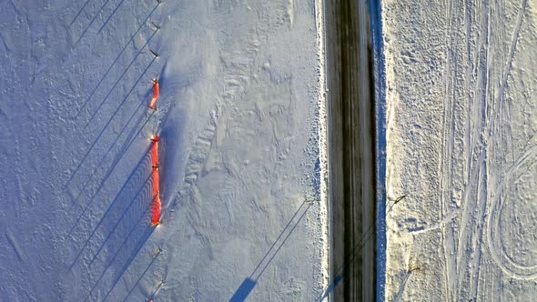 Snowy hay balls and black road in winter, aerial view