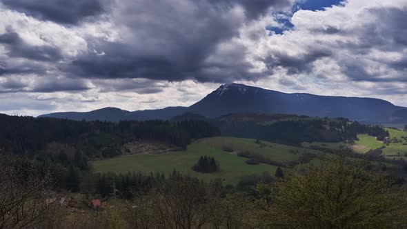 Movement of Dense Clouds Over the Spring Landscape with a Pointed Mountain