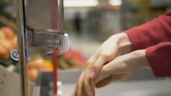 Woman's Hands Close-up Disinfects Her Hands with a Sanitizer in a Grocery Supermarket. Protection