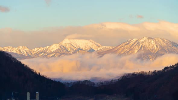 Time lapse of aerial view of snowy mountain hills with morning mist or fog at sunrise