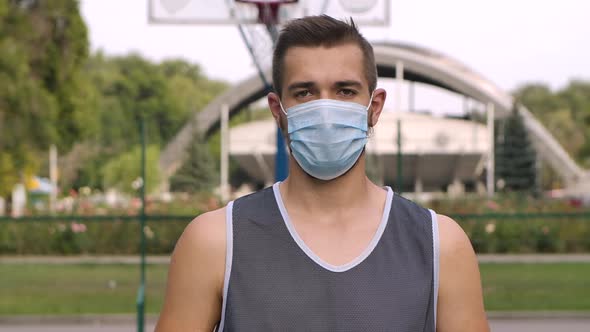 Portrait of Basketball Player in a Medical Mask Standing on Playground and Looking at Camera