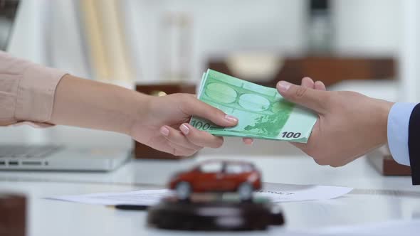 Female Buyer Giving Car Trader Euros, Shaking Hands, Automobile Toy on Table