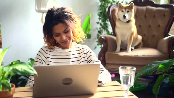 Happy Woman Working with Laptop Computer and Smiling While Sitting at Table in Home Room Spbd