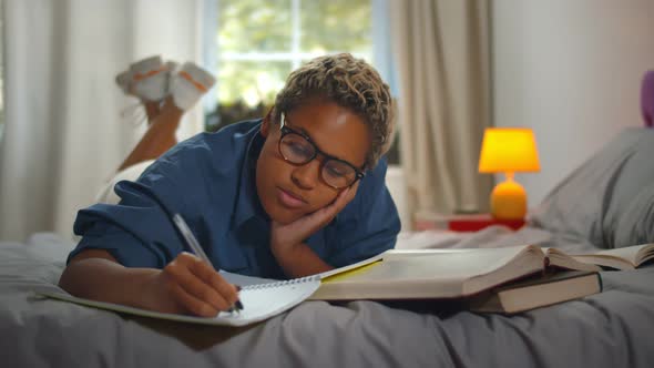 Pretty Young African Female Student Lying on Bed Studying at Home