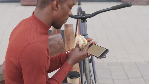 African-American Man Looking at Smartphone during Lunch Break