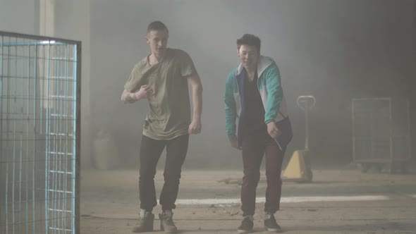 Two Young Men Dancing in the Dark and Dusty Room of Abandoned Building