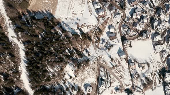 Top down drone shot over winding roads to ski chalets covered in snow