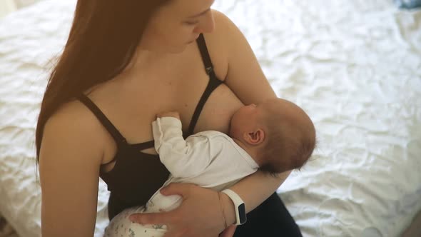 Mother Breastfeeds Little Baby Girl at Home