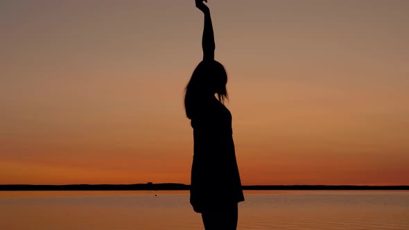 Happy Woman Runs To The Sunset To The Beach Raising Her Arms Up And Spinning