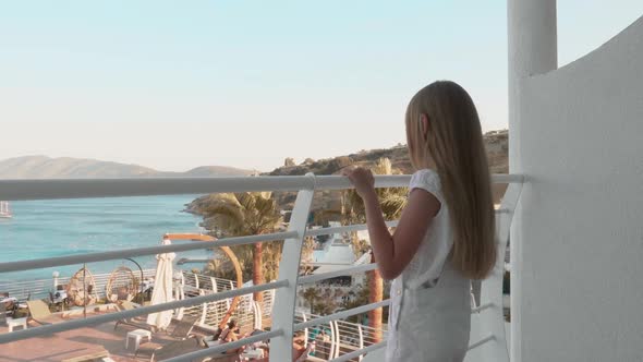 Cute Teenage Girl Standing on Balcony and Looking at Seascape