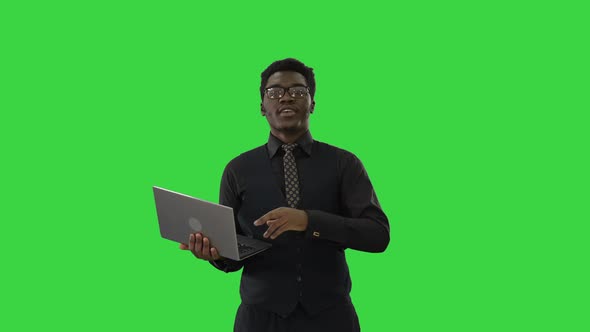 African American Businessman Typing on Laptop and Talking To Camera with a Smile While Gesturing on