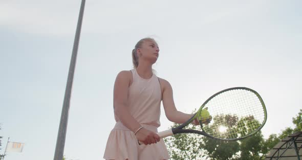 Low Angle Crop View of Woman Serving Ball During Tennis Match on Blue Sky Background