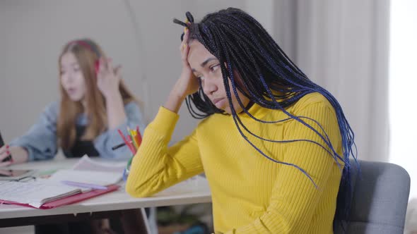 Portrait of Irritated African American Girl with Dreadlocks Holding Head with Hand As Blurred