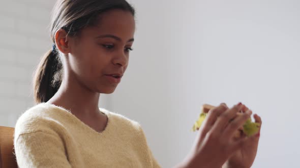 Positive African girl eating sandwich alt