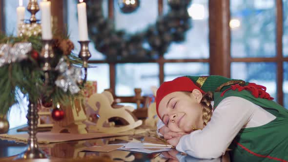 Elf is sleeping at the table indoors.