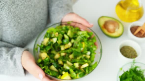 Woman Hands Giving Salad of Fresh Green Vegetables and Herbs