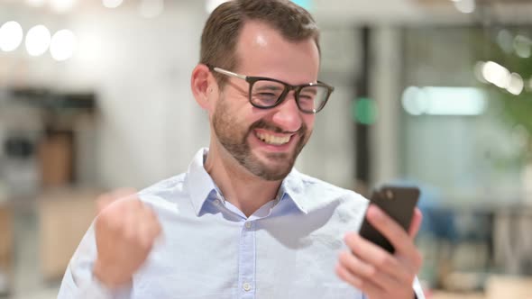 Portrait of Excited Businessman Celebrating Success on Smartphone 