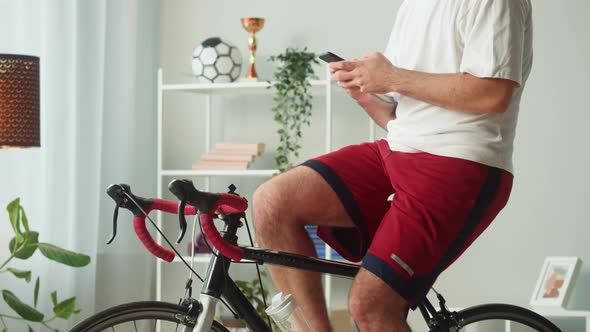 Sportsman Riding Bicycle and Using Phone Home Gym