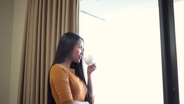 Relaxed woman rest with cup of coffee or tea staying near window