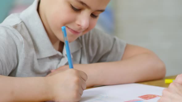 Boy Drawing with Colored Pencil in Kindergarten alt