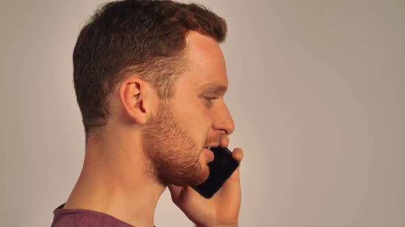 Red-haired Man Is Standing Sideways and Chatting on the Phone, White Background