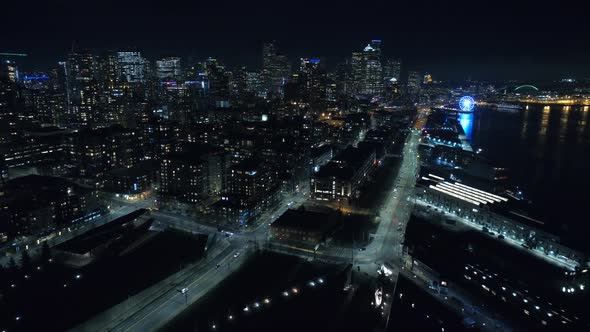 Flying Over City Waterfront At Night With Tall Buildings