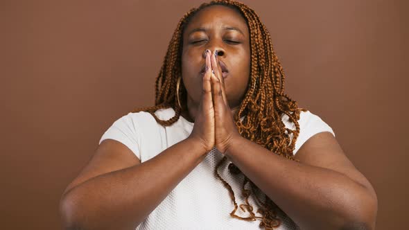 Close Up Portrait of Praying African American Woman Pleading to God Brown Studio Background