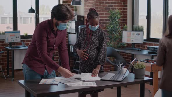 Pregnant Employee Working with Man on Business Charts