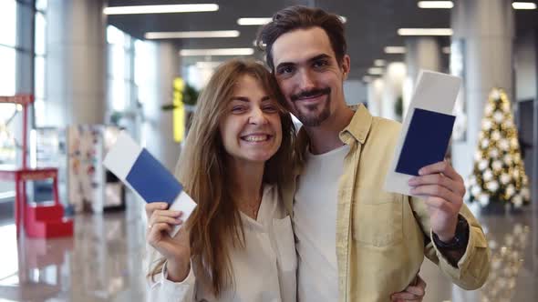 Excited Caucasian Couple Going on a Vacation and Holding Passport Boarding Pass at Airport