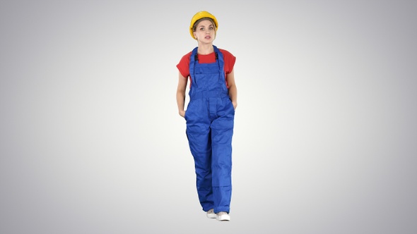 Woman builder with hands in pockets walking and telling