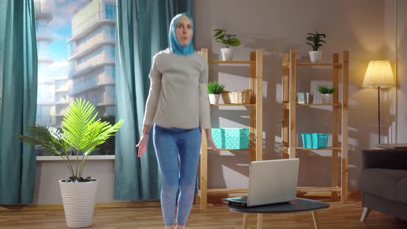 Young Muslim Woman Plays Sports in the Living Room in Front of Her Laptop