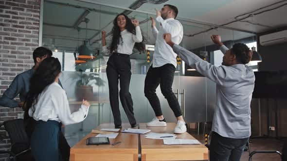Multiracial Colleagues Dancing in Office Celebrating Victory Company Success Good Deal Man and Woman