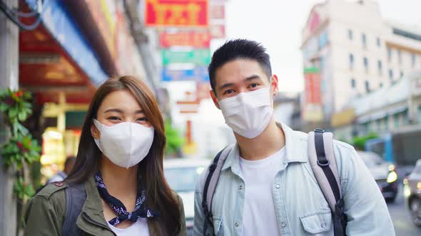 Portrait of Asian couple wear mask, travel in city for honeymoon trip.