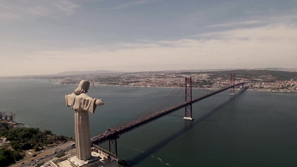 Aerial descending shot of outstretched arms of Christ the King sanctuary projected towards Lisbon